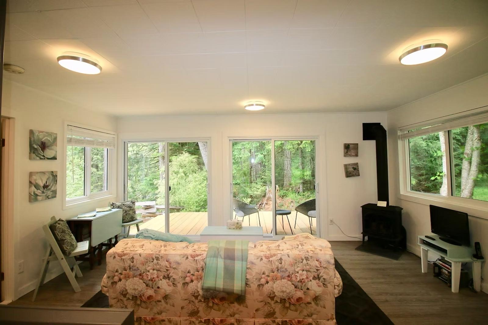 Bright forest cabin interior with sliding doors to the trees and a wood stove